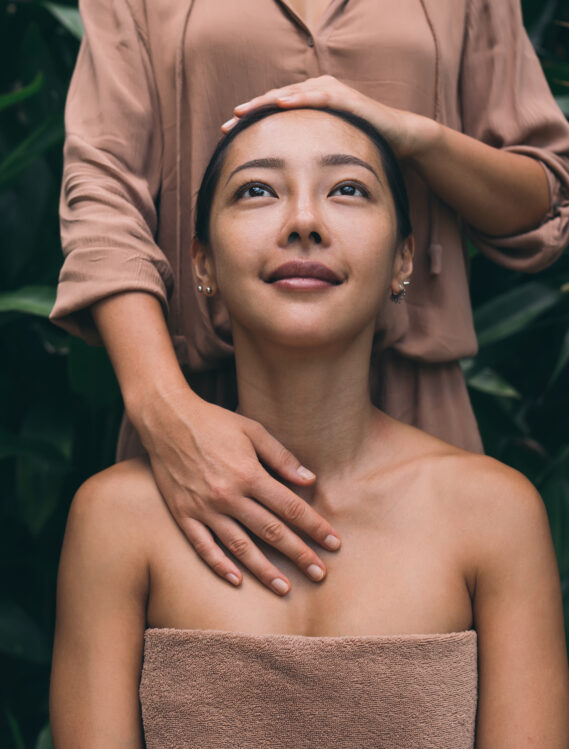 Attractive Asian woman enjoying time for herself visiting beautician or cosmetologist for doing skin procedures on nature, charming brunette female feeling wellness during body massage therapy