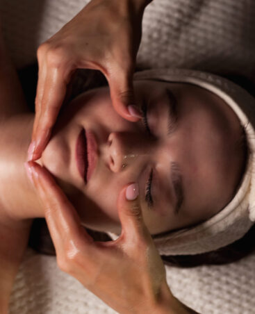 Relaxation unfolds as a skilled therapist applies a facial massage to a client in a serene indoor environment. The soft light enhances the soothing atmosphere.
