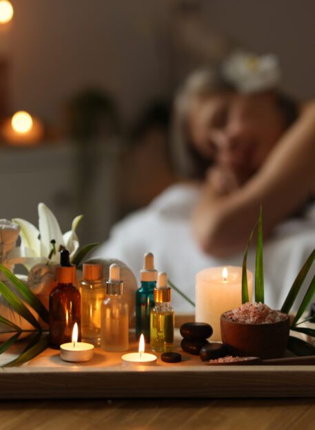 Senior woman relaxing on massage couch indoors, focus on different spa products